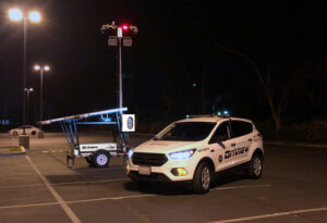 Solar security trailer and security patrol vehicle in a parking lot